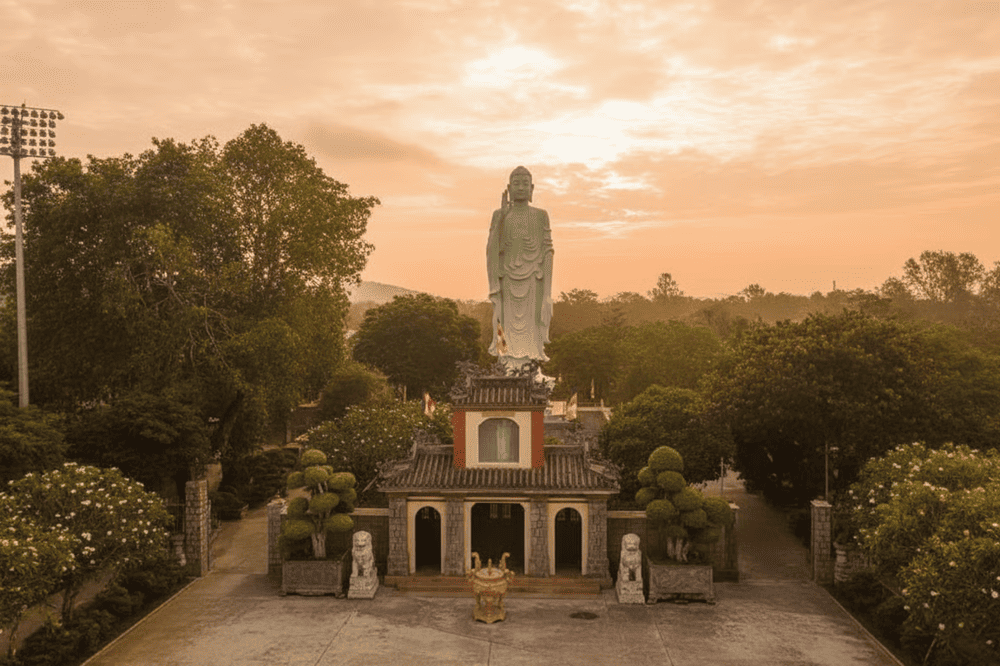 The Tam Quan gate is built of sturdy green stone, behind it is the statue of Amitabha Buddha